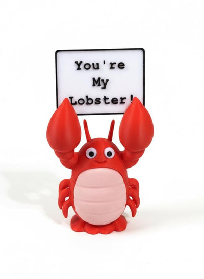 3D printed lobster figurine in hand showing 4-inch scale on white background