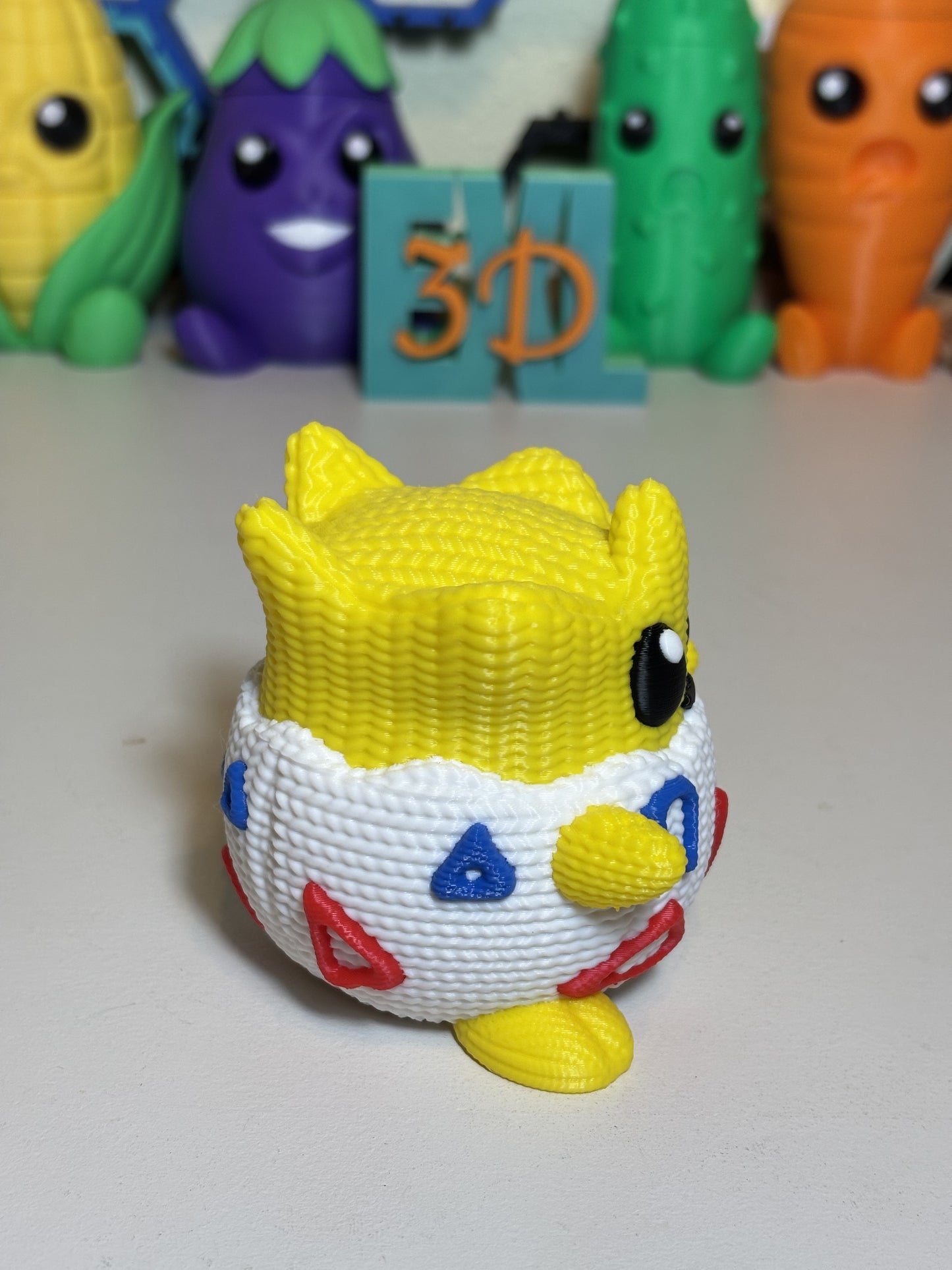 Side angle of 3D printed Togepi faux knit statue on white background
