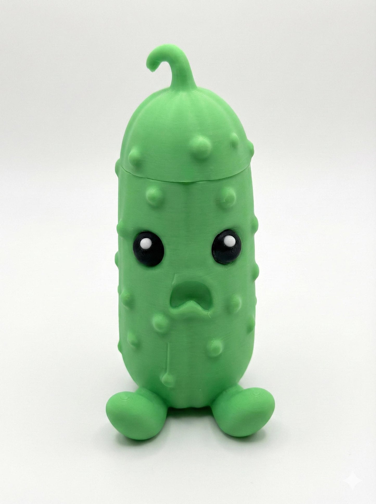 Vibrant green 3D printed pouty pickle figurine with hidden compartment open on desk