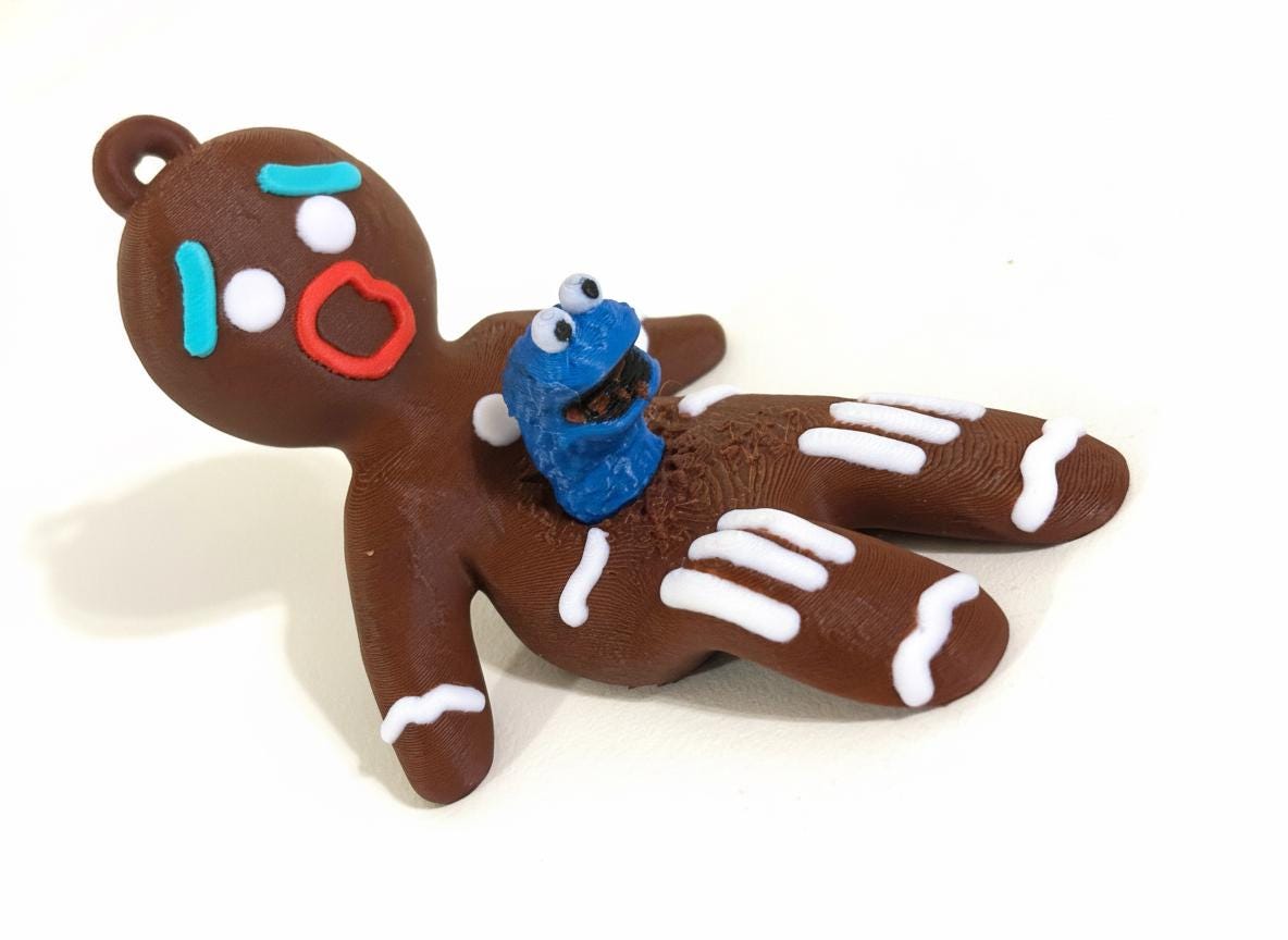 3D printed gingerbread chestburster ornament hanging on Christmas tree with blue creature emerging