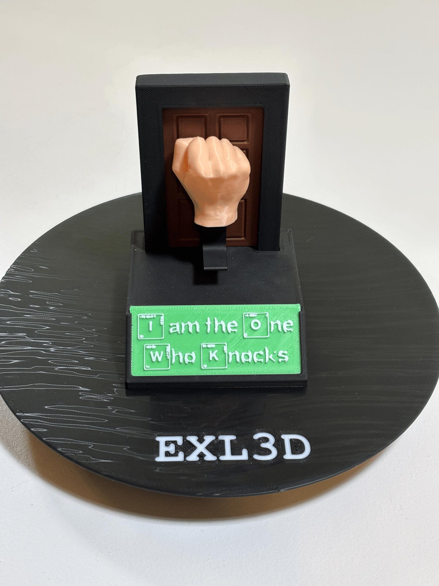 Spring-loaded matte black kinetic desk toy with wood-grain door detail