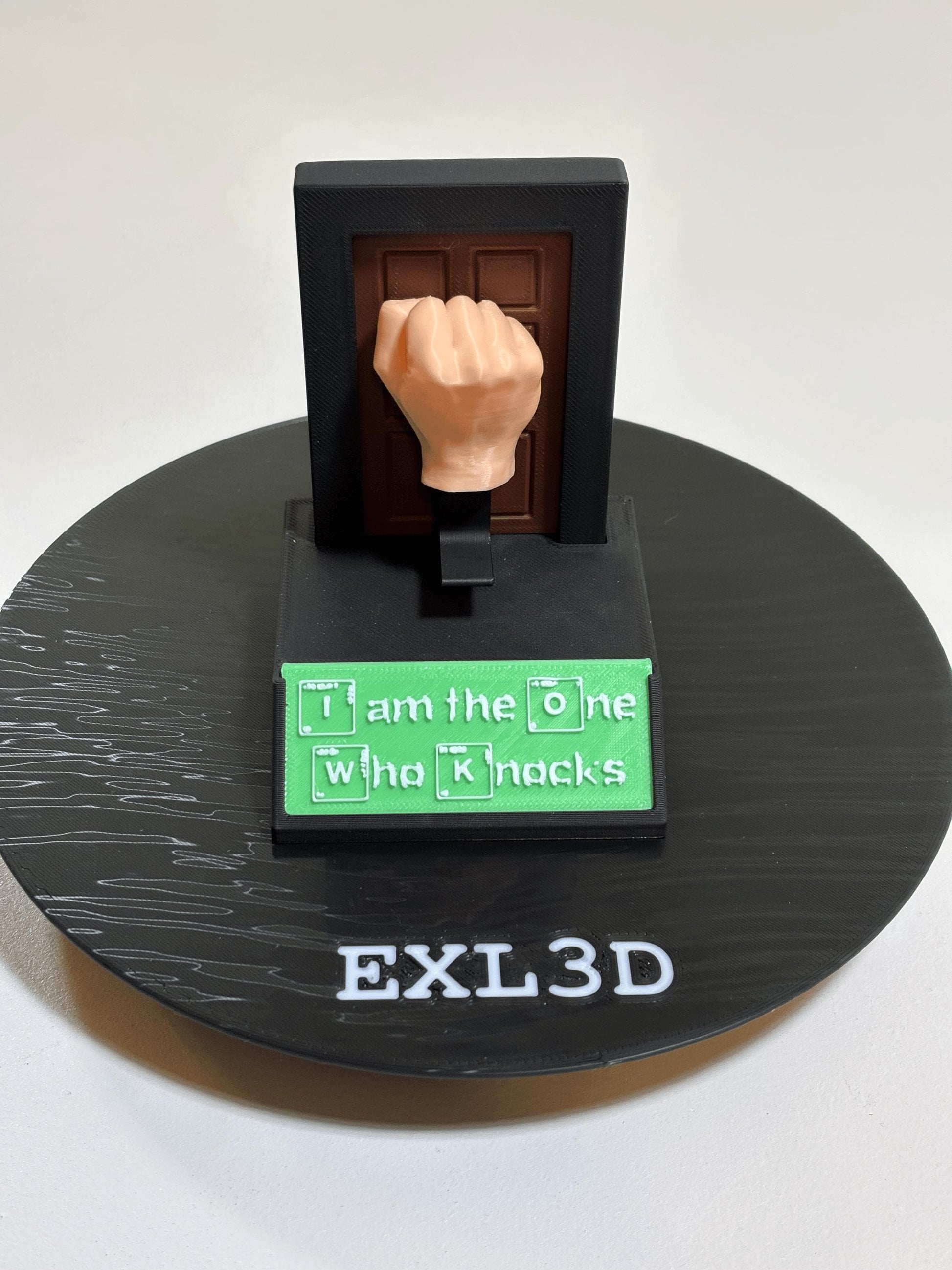 Spring-loaded matte black kinetic desk toy with wood-grain door detail