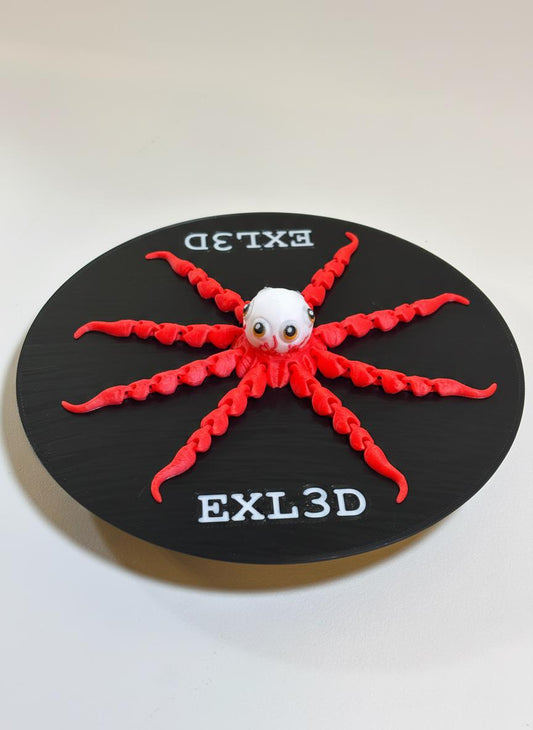 Red and white 3D printed alien octopus flexi toy on neutral desk surface