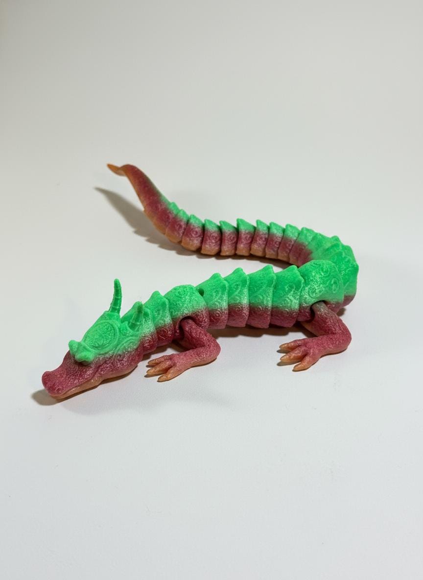 Rainbow gradient 3D printed dragon draped over hand showing flexible joints