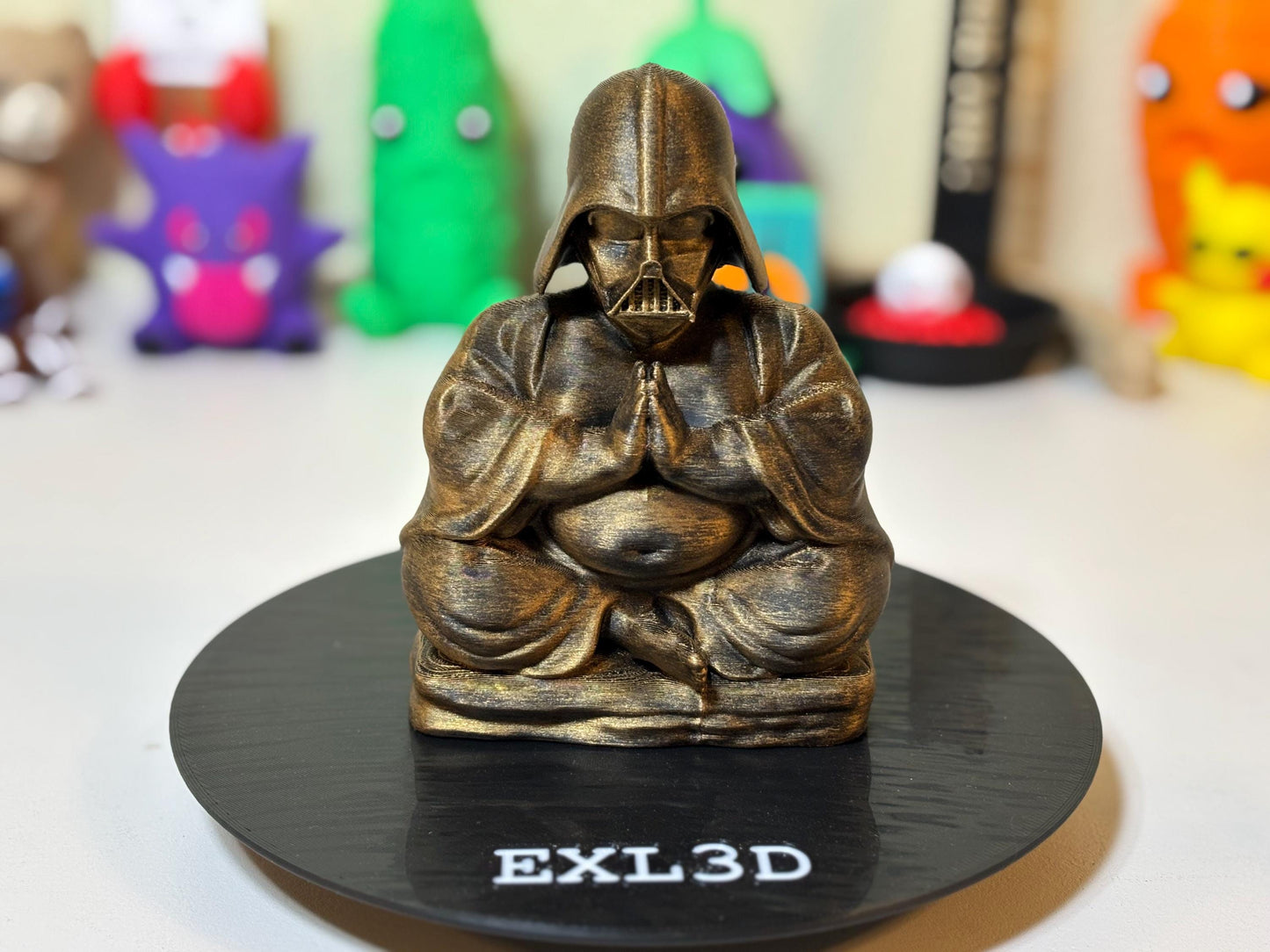 Bronze metallic 3D printed meditation statue shown on a wooden bookshelf