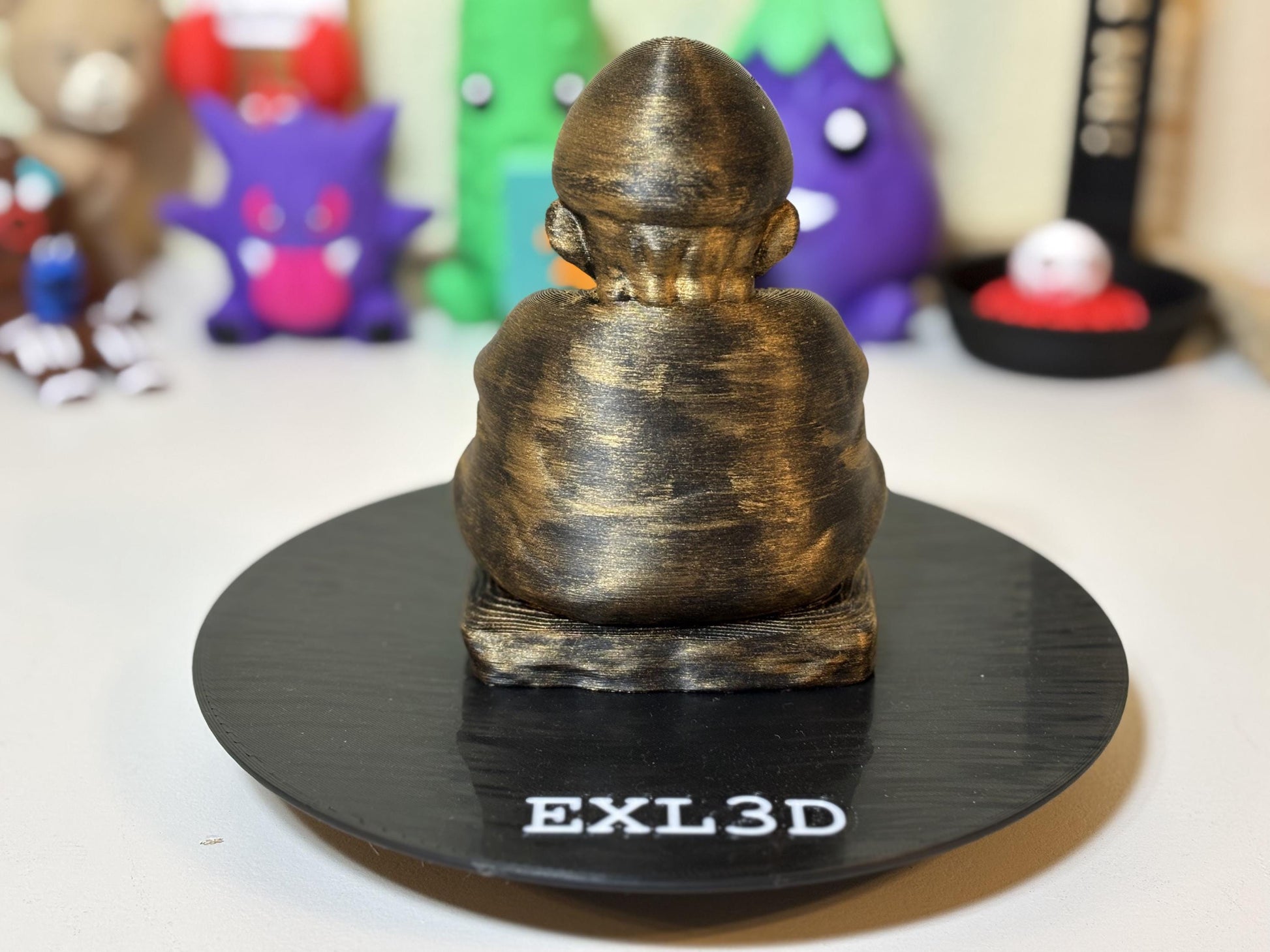 Bronze Buddha plumber statue on bookshelf with gaming collectibles