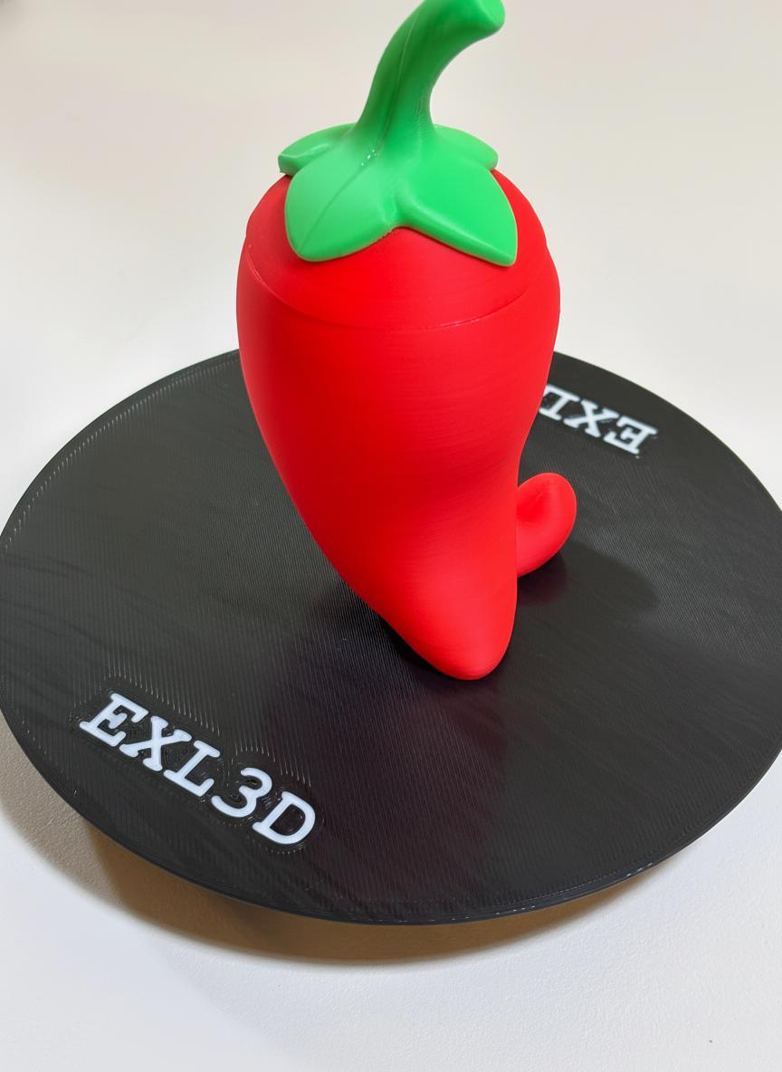 3D printed chili pepper statue beside small jewelry and loose change