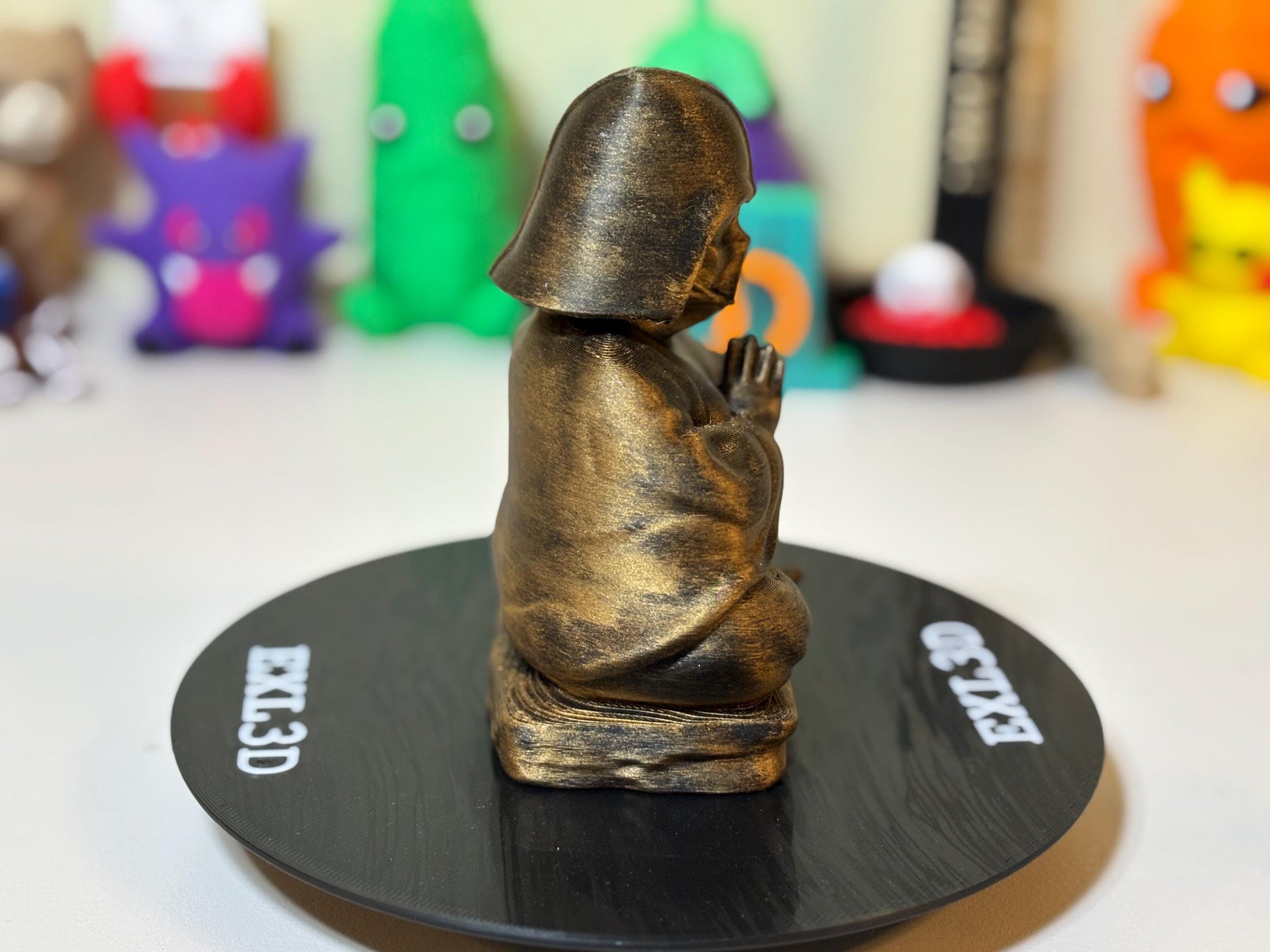 All three finish options of 3D printed Buddha statue — gold, silver, and bronze on black
