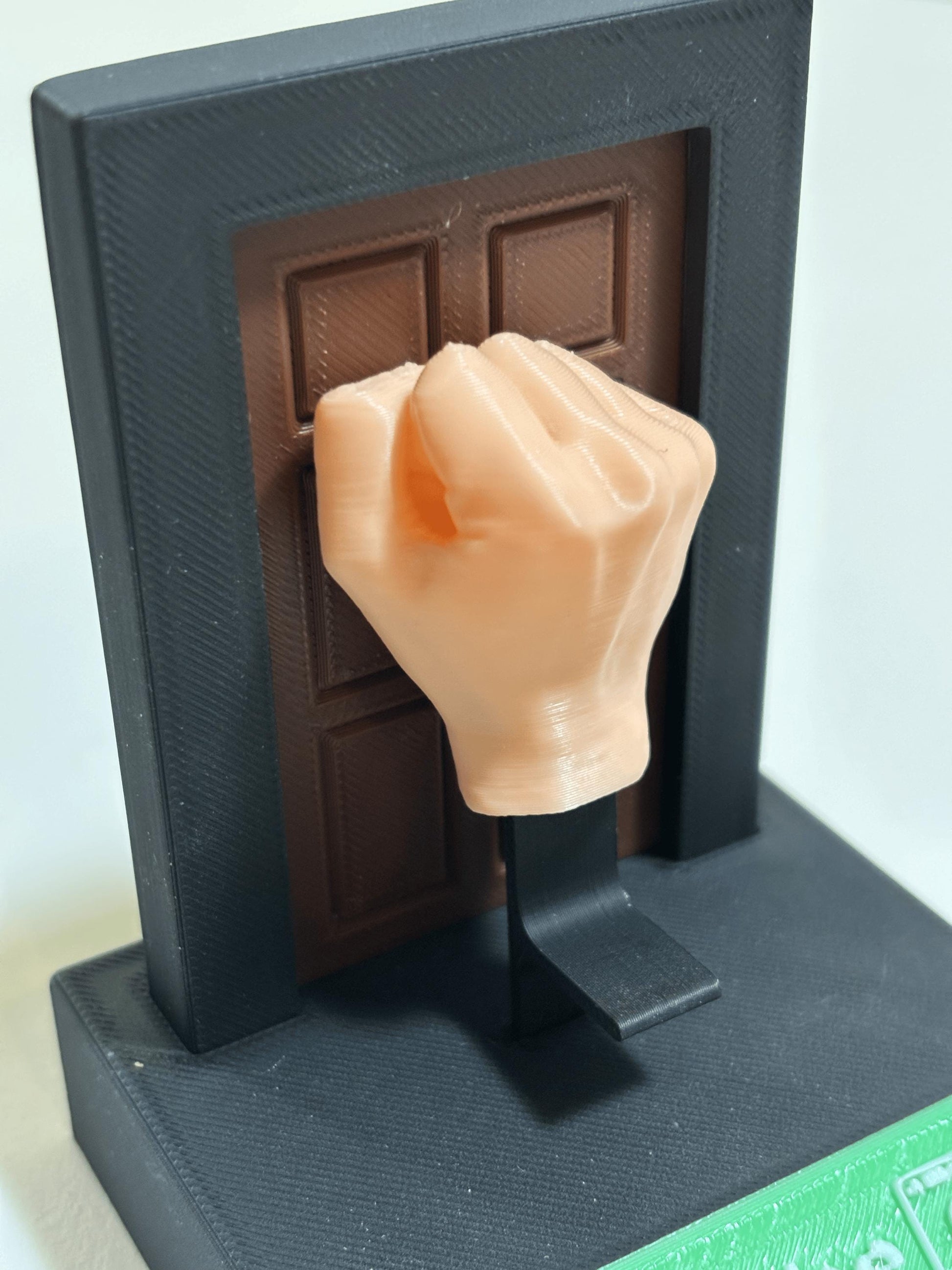 3D printed fist fidget toy shown from front angle on desk surface