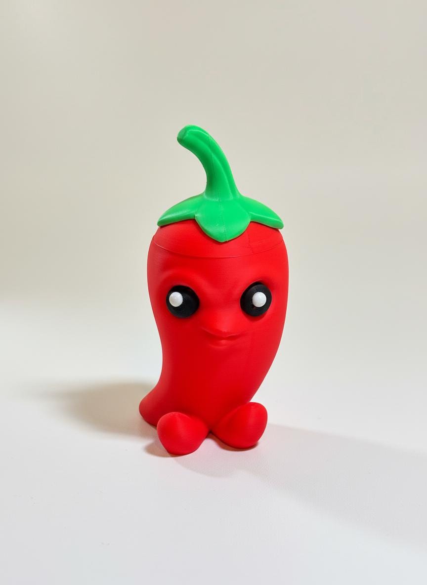 Bright red 3D printed chili pepper stash box on a wooden desk