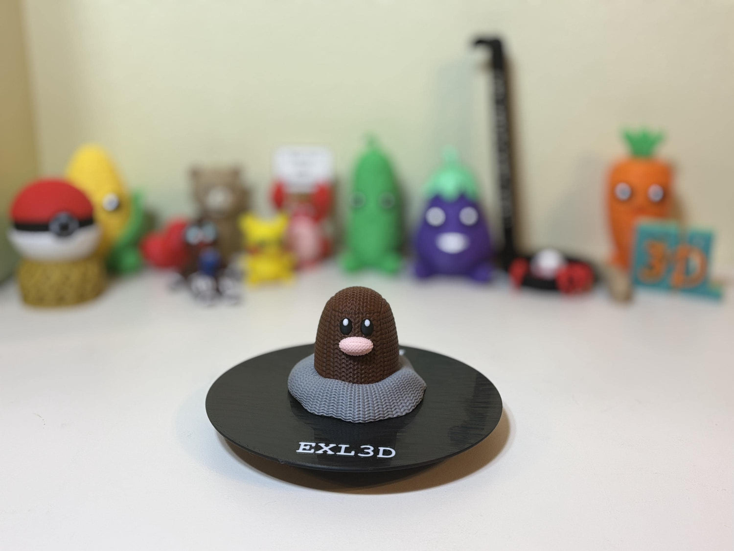 3D printed mole figure with faux knit texture emerging from dirt base on desk