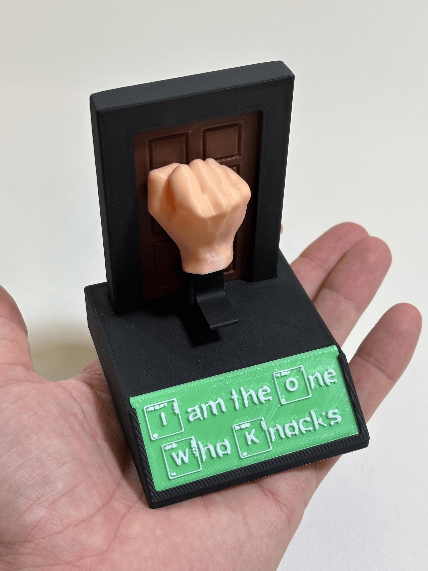 Palm-held view of flesh-tone fist and matte black base showing full size