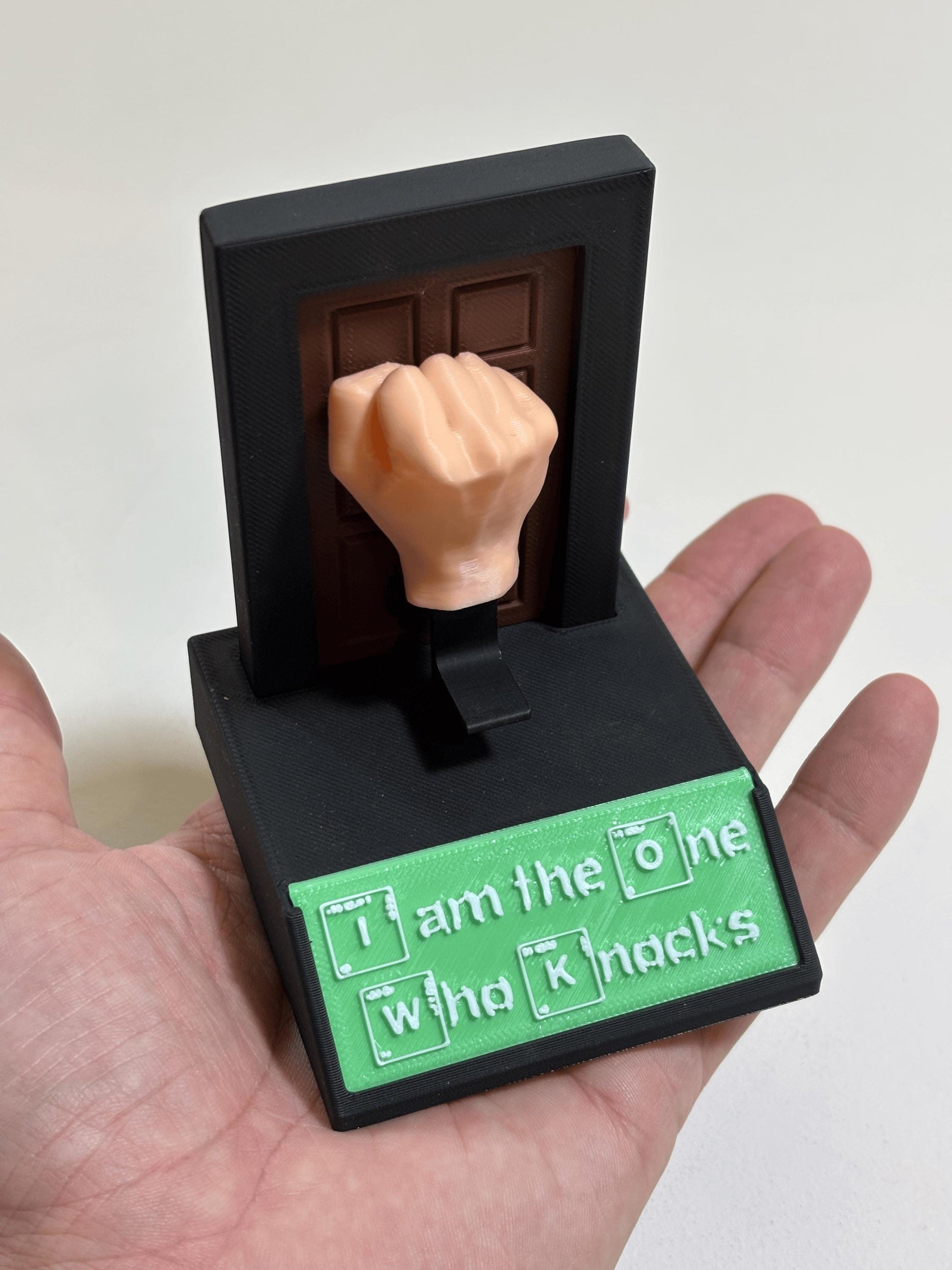 Palm-held view of flesh-tone fist and matte black base showing full size