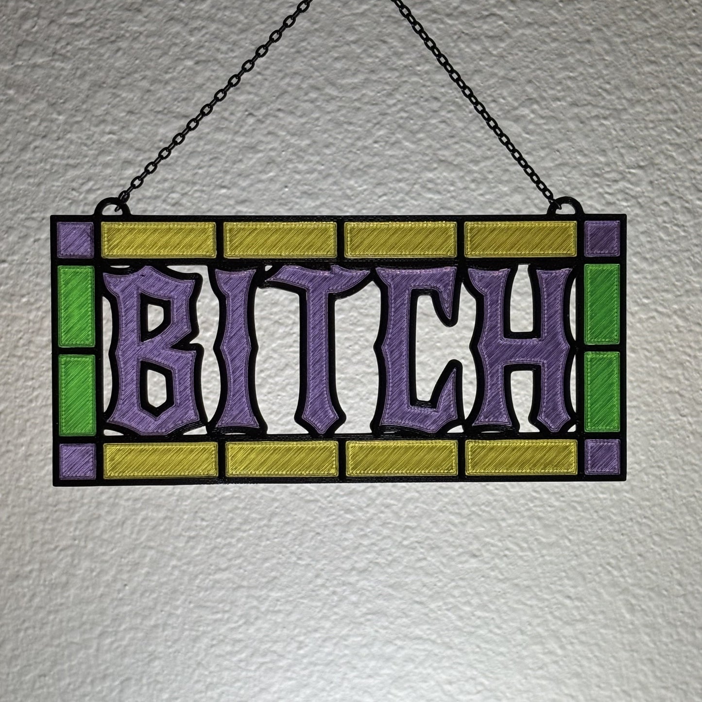 Bold text detail shot on profane 3D printed stained glass style suncatcher