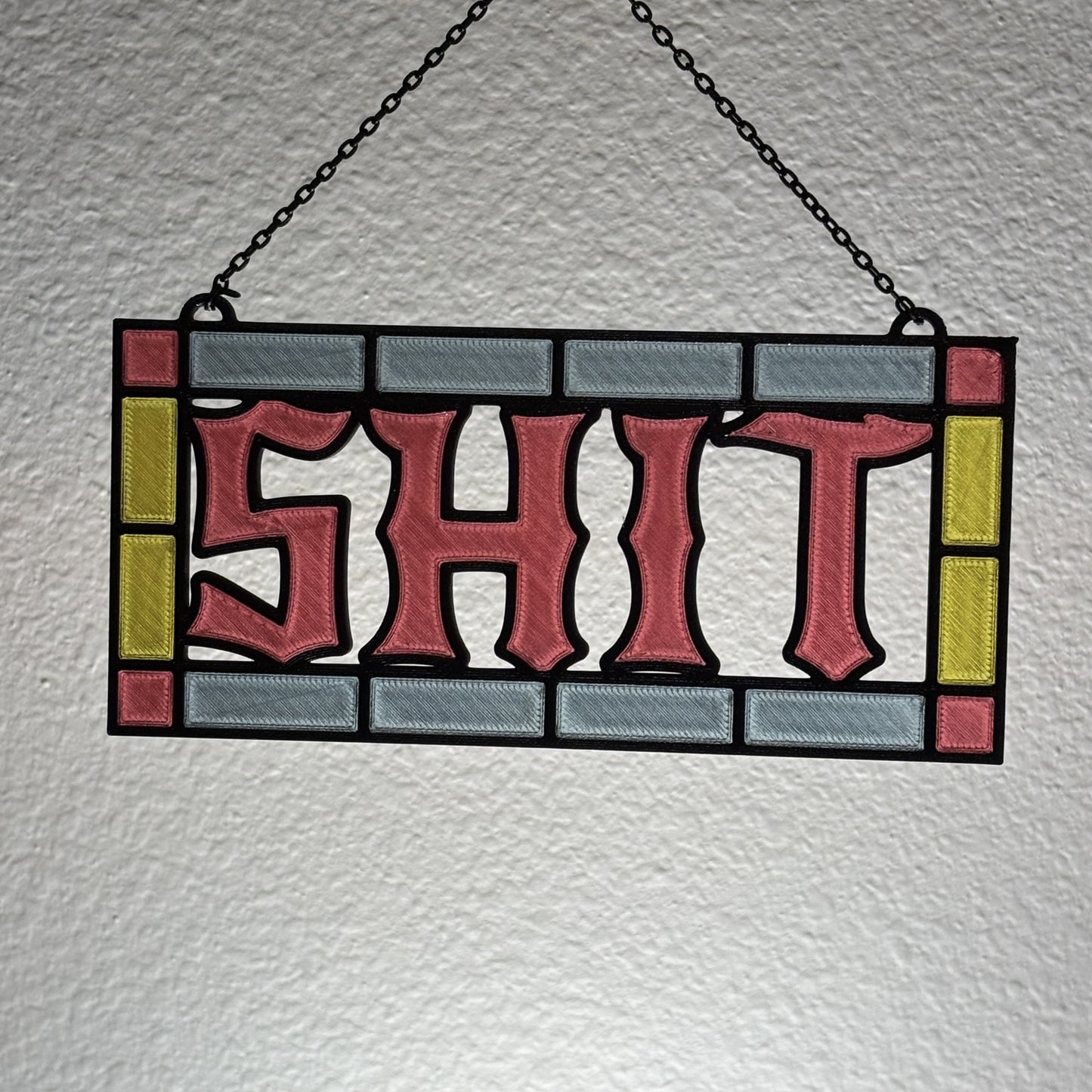 Profane stained glass style suncatcher hanging from black decorative chain