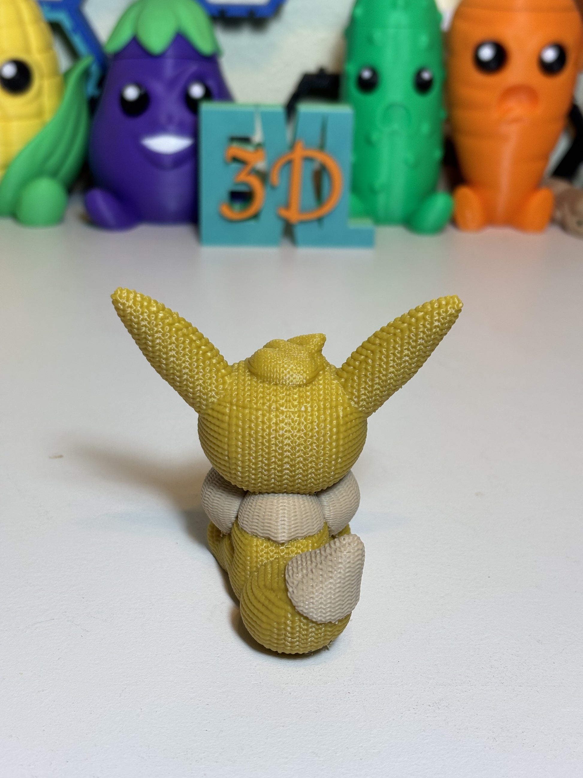 Faux knit Eevee 3D sculpture posed on shelf with gaming decor