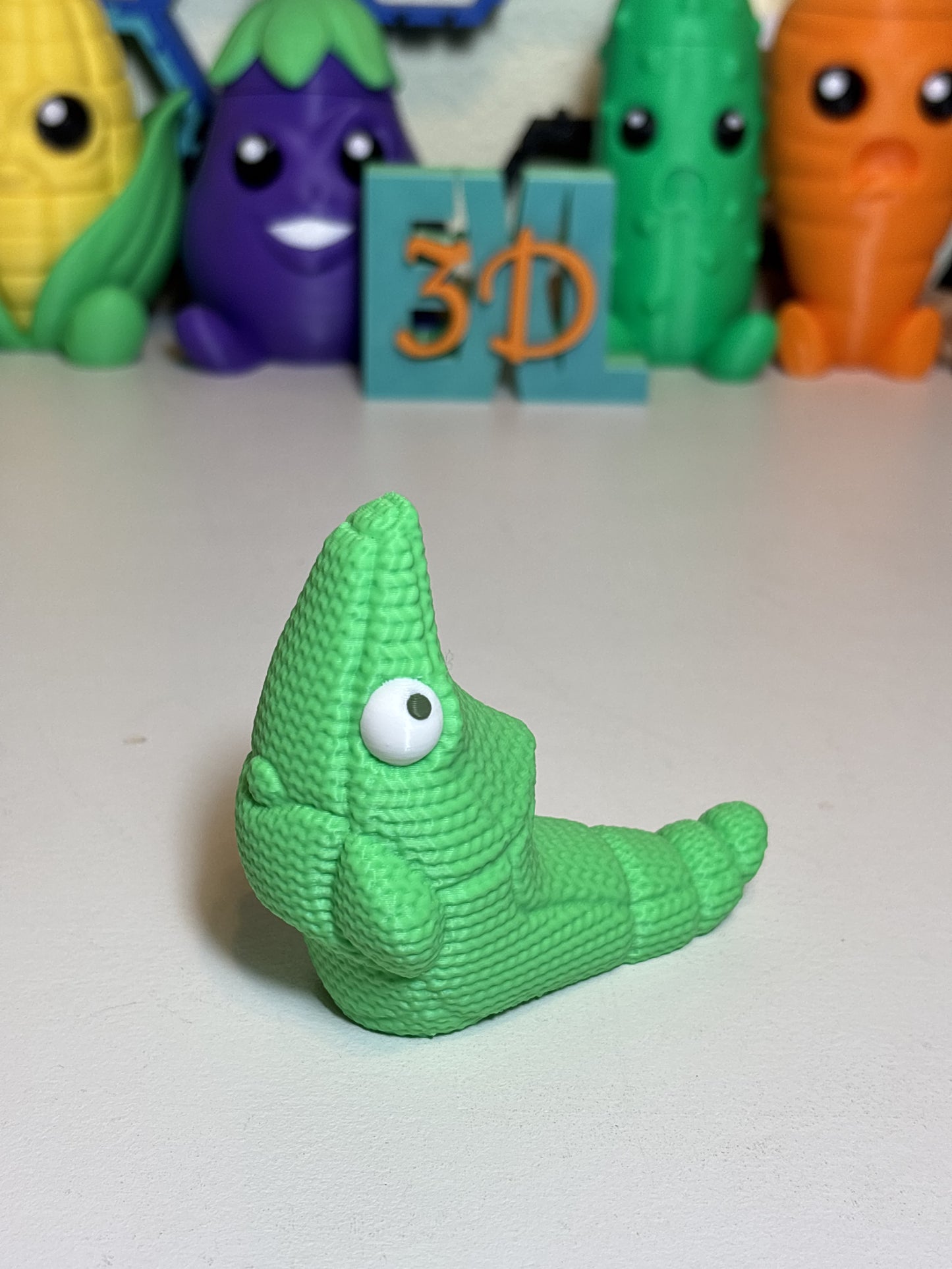 Faux knit Metapod 3D printed decorative statue on wooden desk surface