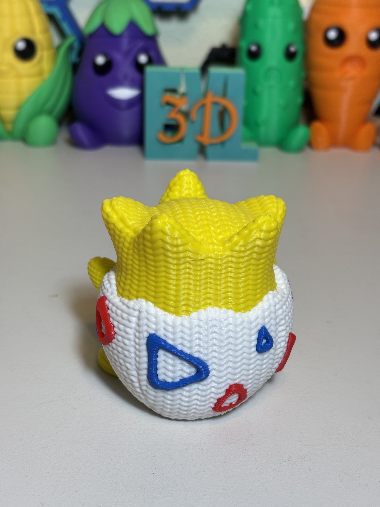 Faux knit Togepi figurine beside small plants as shelf decor